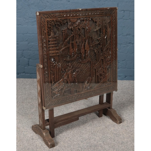 436 - A wooden tilt top occasional table with carved oriental scene.