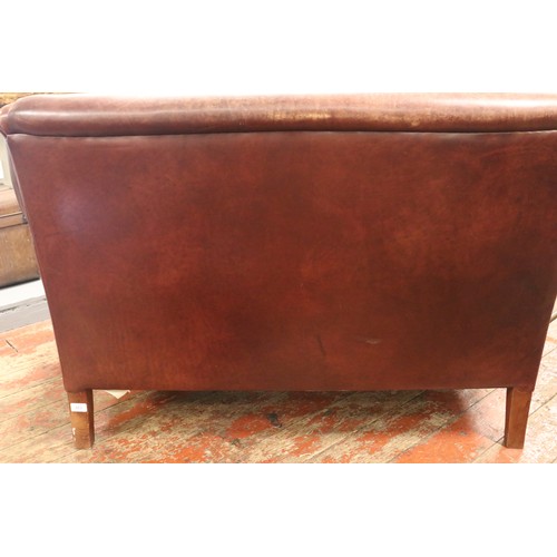 438 - A brown leather two seater sofa, with Liberty style cushions.