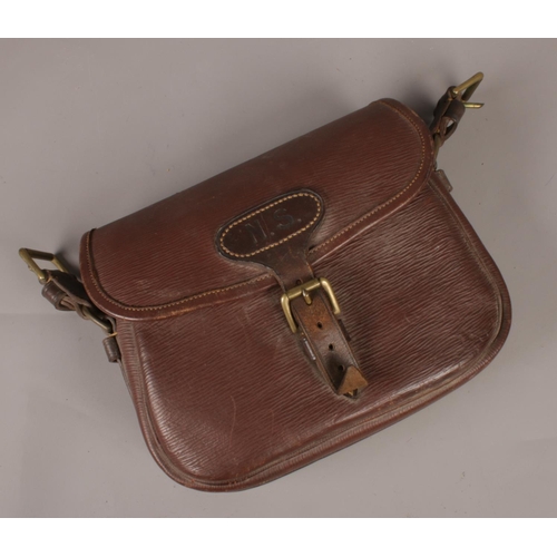 84 - A brown leather cartridge satchel. Monogrammed NS. Includes some contents of gun cleaning equipment.