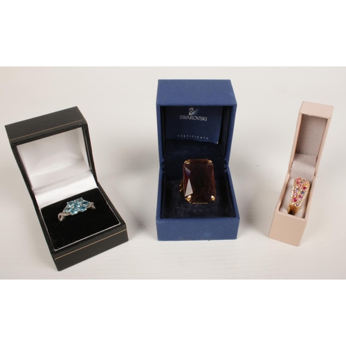 413 - A Swarovski dress ring set with large purple stone along with two other dress rings.