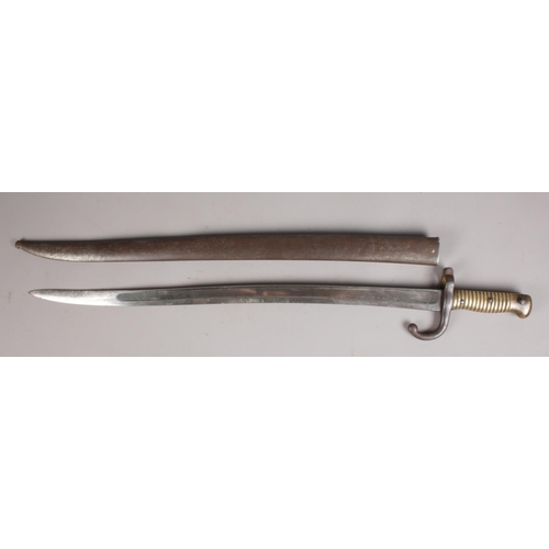 75 - A French 1868 pattern sword bayonet in scabbard. With brass grip. Inscription to edge of blade. Hilt... 