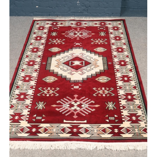 515 - An Aztec style wool & silk rug in red, cream and pale green. H:205cm, W: 128.5cm.