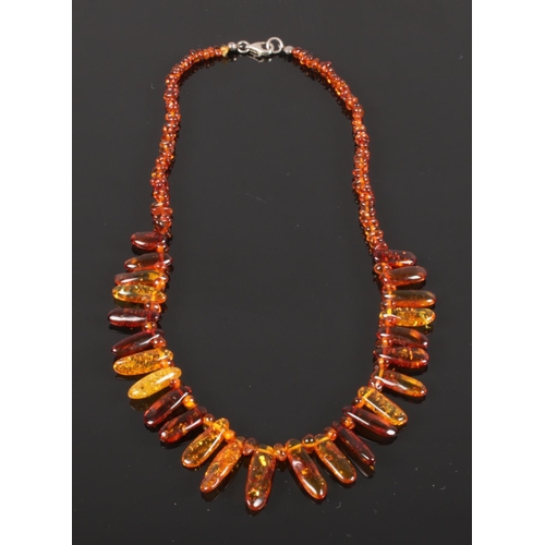 593 - A cased cognac amber necklace comprising approximately 150 shaped and graduated beads with safe lock... 