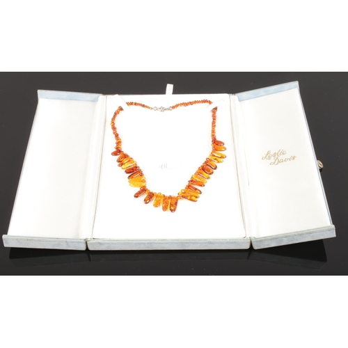 593 - A cased cognac amber necklace comprising approximately 150 shaped and graduated beads with safe lock... 