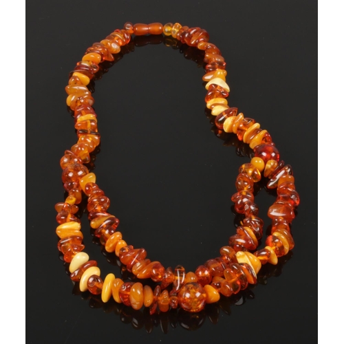 596 - An opera polished amber necklace comprising of cognac, butterscotch and blonde amber with screw cup ... 