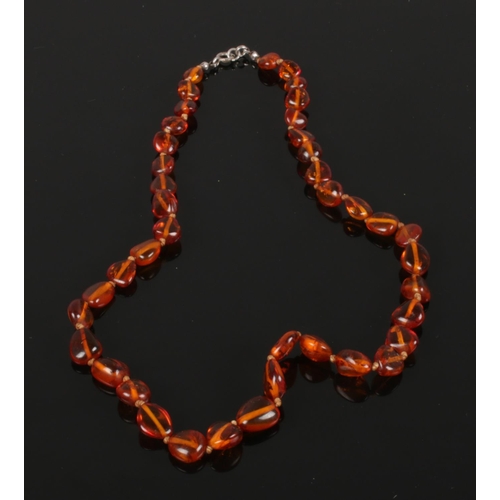 599 - A polished cognac amber graduated necklace with silver clasp 49cm long