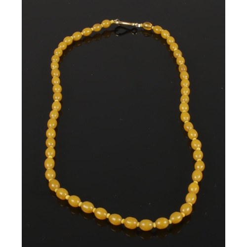 600 - A honey amber necklace each ovoid bead divided with tiny yellow spacers, yellow metal dog clip faste... 