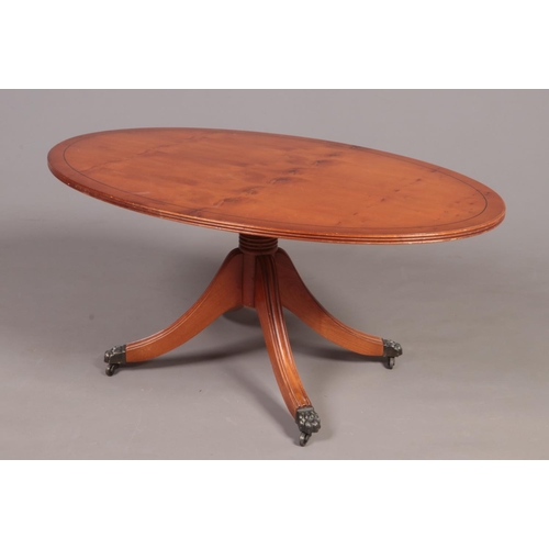 316 - A Yew wood Regency style oval coffee table -  with down swept legs & four paw feet on casters. H: 48... 