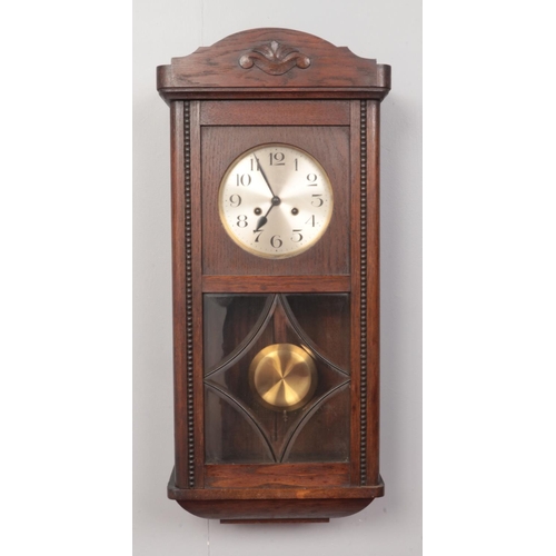 148 - A carved oak eight day wall clock. With silvered dial and rod chiming.