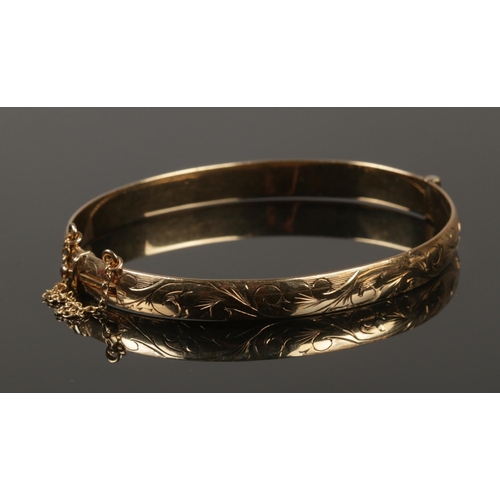 231 - A 9ct gold bangle with engraved decoration. 17g.