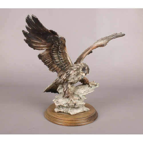 61 - A composite figure of an eagle on a wooden plinth. Monogramed on the figure. H: 32cm, W: 37cm.