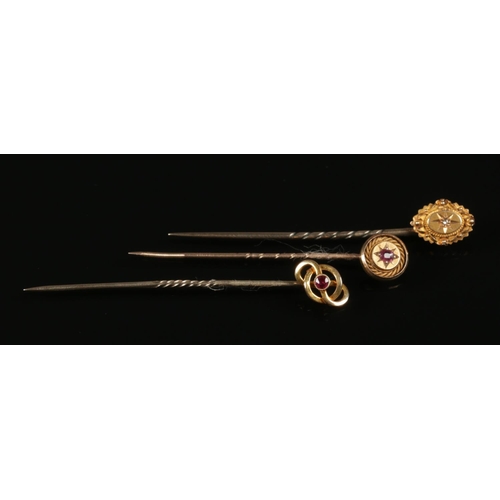 248 - Three 15ct gold stick pins, two set with rubies and the other with a diamond.