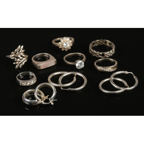 255 - A collection of silver jewellery. Includes seven rings and three pairs of hoop earrings.