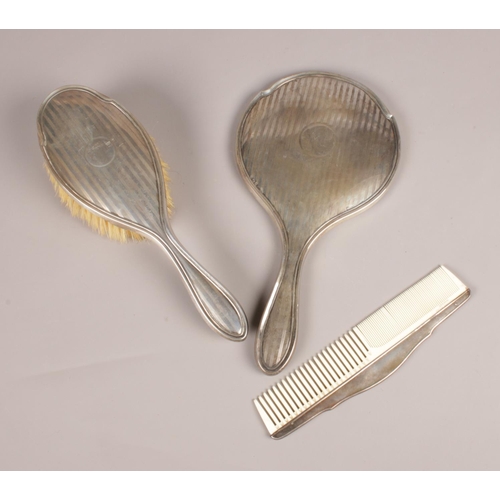 287 - A silver bedroom set. Hairbrush, comb, hand mirror, assayed Birmingham various maker marks.