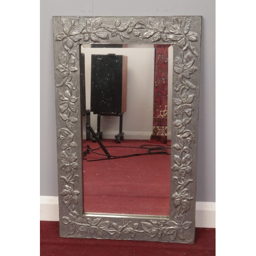 191 - A floral edged metal wrapped mirror with bevelled glass. H: 74.5cm,W: 46cm.