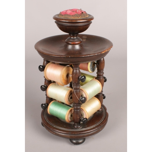 71 - A Victorian turned mahogany bobbin stand with pin cushion top.