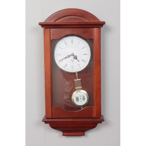 410 - A wooden cased wall clock with pendulum and quartz movement. H: 52cm, W:26.5cm.