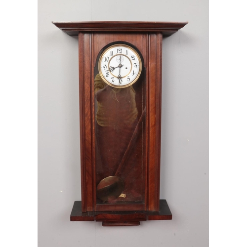 418 - A Mahogany cased 8 day wall clock with pendulum and twin weights. Comprising of a glass fronted door... 