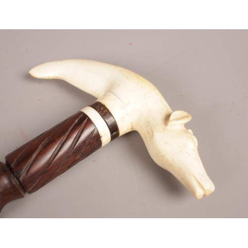 86 - An African tribal carved wooden stick with ivory handle formed as a cow.