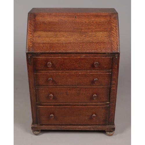 332 - An oak bureau with fitted interior and four drawers.