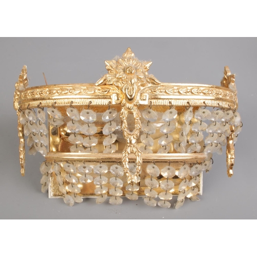 255 - A set of three gilt metal wall lights with crystal drops. H:14cm, W:22cm.