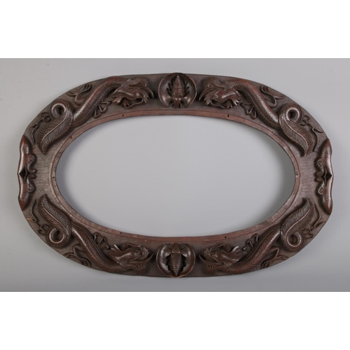 313 - An oval carved hardwood frame decorated with dragons and bats. H: 37cm W: 57cm.