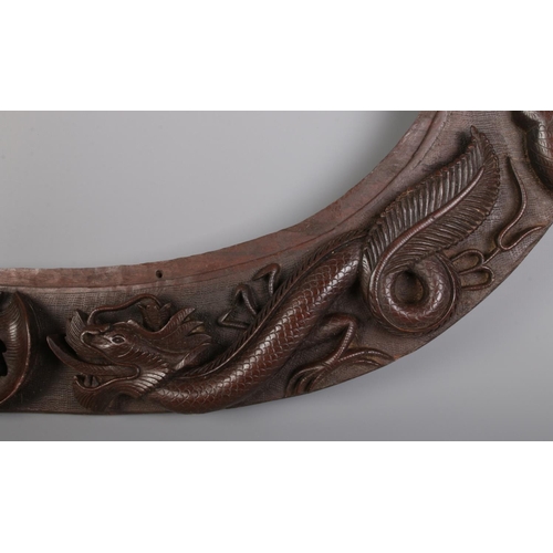 313 - An oval carved hardwood frame decorated with dragons and bats. H: 37cm W: 57cm.