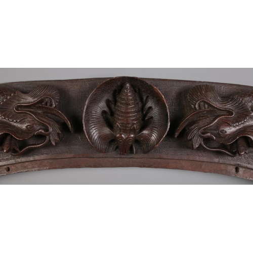 313 - An oval carved hardwood frame decorated with dragons and bats. H: 37cm W: 57cm.