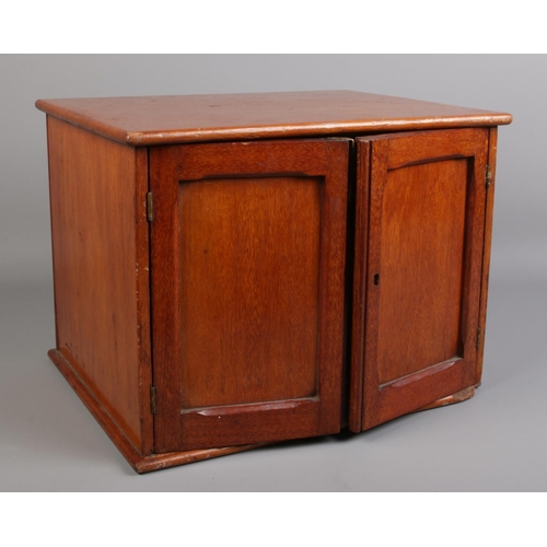 99 - A vintage mahogany coin chest with panelled doors.