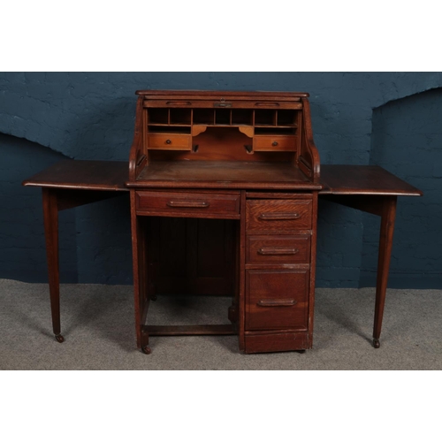 439 - An early 20th century oak roll top bureau with gate leg extensions. Raised on casters. H:117cm W:79c... 