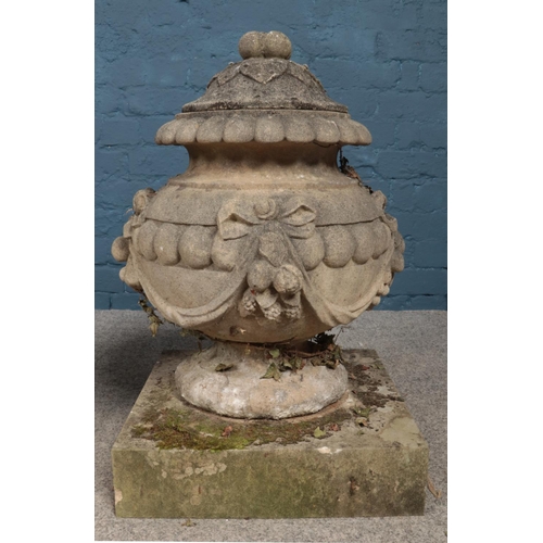 293 - A large pair of carved stone lidded garden urns of Neoclassical design, with swag and bow decoration... 