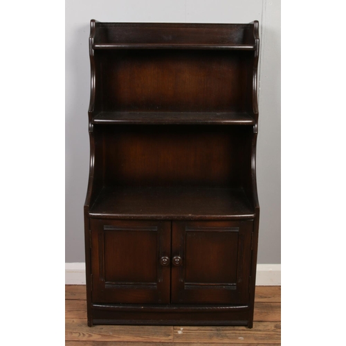 532 - An Ercol open waterfall bookcase with cupboard base.