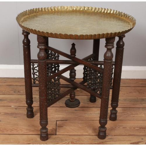 526 - An Eastern brass top table with folding base.