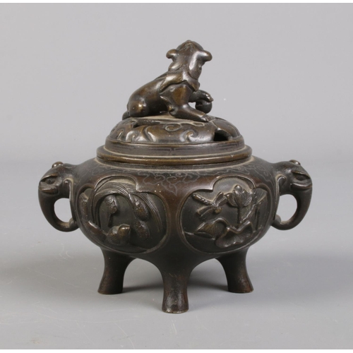 100 - A Chinese bronze lidded censor. The lid surmounted with a temple lion and having elephant mask handl... 