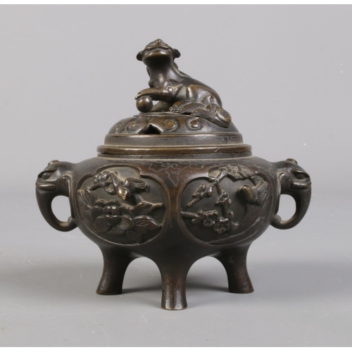 100 - A Chinese bronze lidded censor. The lid surmounted with a temple lion and having elephant mask handl... 