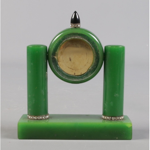 131 - An Art Deco travelling clock in case. Possibly green bakelite housing a gilt metal timepiece.