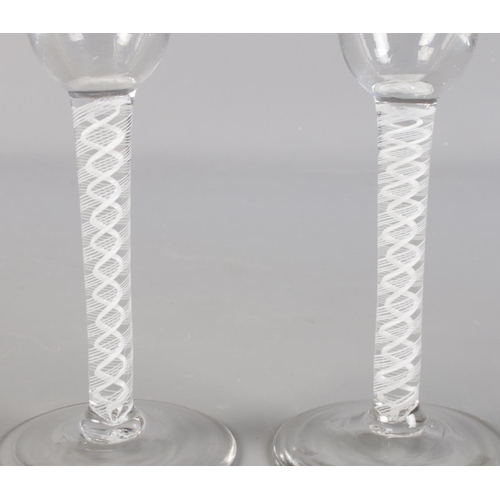 22 - A near pair of 18th century wine glasses with double opaque air twist stems and circular feet. 15cm ... 