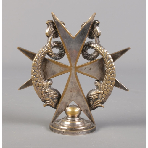 49 - A silver plated Cutajar Works car mascot formed as a Maltese cross surmounted with two dolphins.