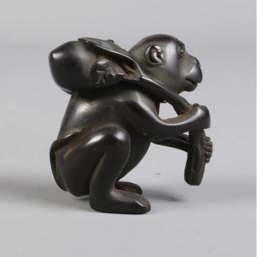 93 - A carved wood netsuke formed as a monkey carrying fruit.