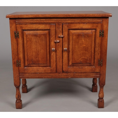 649 - A carved and panelled oak side cabinet. Possibly Titchmarsh and Goodwin. (76cm x 76cm x 38cm)