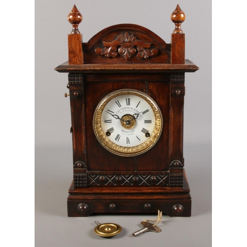 130 - A carved oak Fattorini & Sons mantel clock. Patent automatic alarm. With pendulum and key.