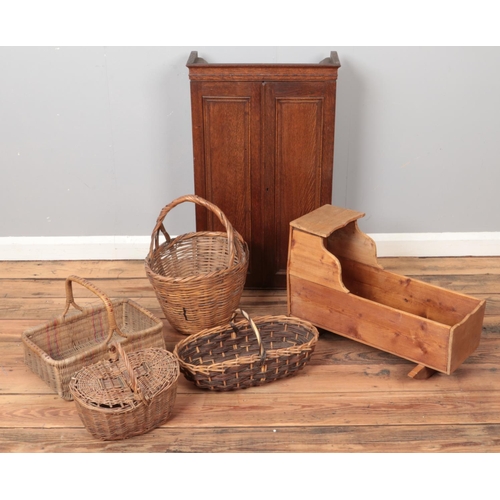 290 - An oak wall cabinet along with a babies rocking crib and wicker baskets.