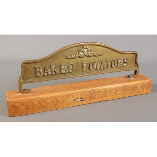 62 - A brass Baked Potatoes sign mounted to wooden base.