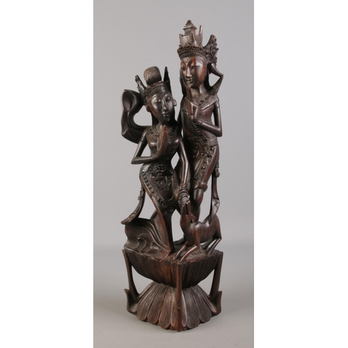 104 - An extensively carved hardwood tribal figure group, depicting dancing girls. 53cm high.