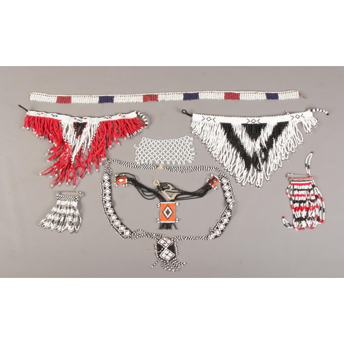 67 - A collection of African beadwork jewellery, to include necklaces and pin on brooches.