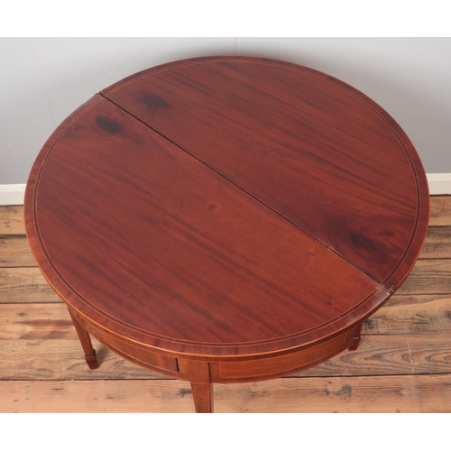 434 - A mahogany demi lune fold over table with lockable drawer and key.