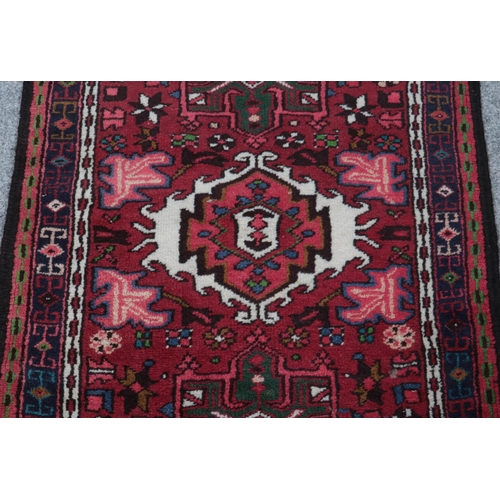 335 - A Persian red ground wool runner. With a geometric pattern within a border. L:209cm W:70cm.