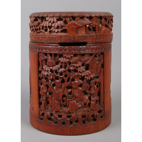 126 - A Japanese bamboo tea caddy of cylindrical form, with carved scenes. 16cm high.