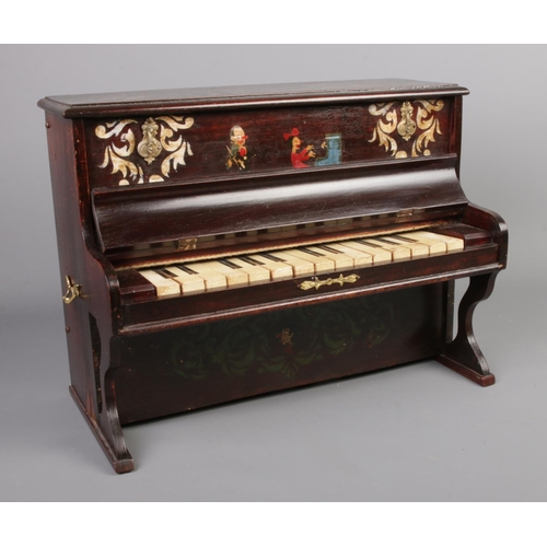 177 - A miniature mahogany piano, with musician figures to the body. Height: 29cm.