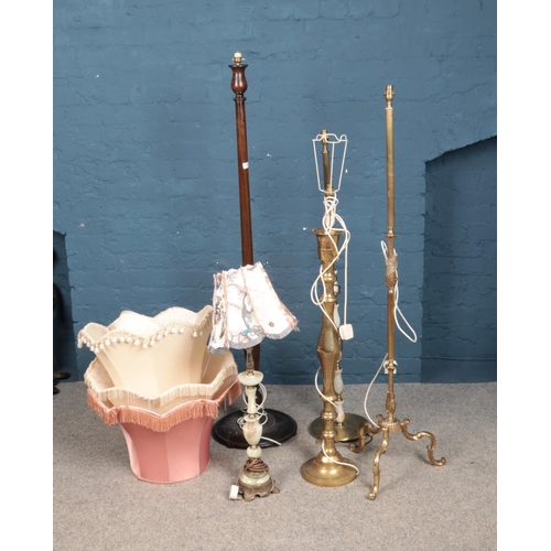 332 - A quantity of five floor lamps including brass and wood examples. Includes a variety of fabric shade... 